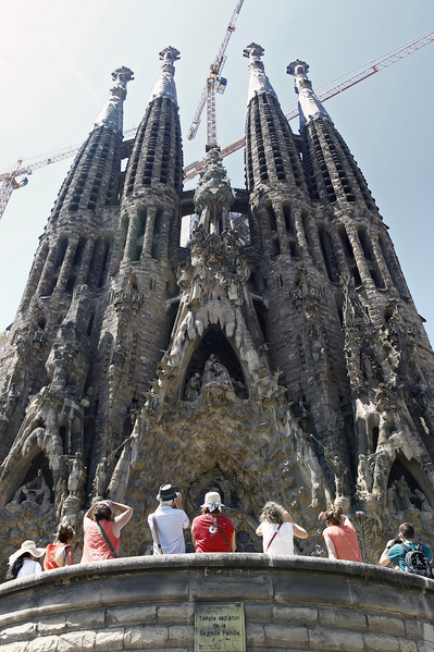 A group of tourists watch the facade of Spanish architect Gaudi's Sagrada Familia basilica in Barcelona on June 28, 2015. Tourists generated 14% of municipal GDP, but these 27 million visitors in Barcelona are a headache for the new mayor Ada Colau , who wants to prevent this Mediterranean port from becoming a theme park. AFP PHOTO / QUIQUE GARCIA TO GO WITH AN AFP STORY BY DANIEL BOSQUE