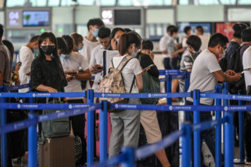 Passengers wait in line in the counter area following preventive procedures against the spread of the COVID-19 coronavirus in Pudong International Airport in Shanghai on June 11, 2020. (Photo by Hector RETAMAL / AFP) (Photo by HECTOR RETAMAL/AFP via Getty Images)