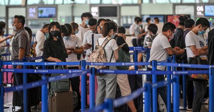 Passengers wait in line in the counter area following preventive procedures against the spread of the COVID-19 coronavirus in Pudong International Airport in Shanghai on June 11, 2020. (Photo by Hector RETAMAL / AFP) (Photo by HECTOR RETAMAL/AFP via Getty Images)